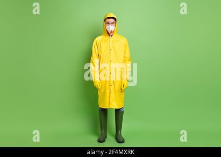 Vue sur toute la longueur de la taille du corps d'un homme sérieux portant un imperméable équipement anti-danger biologique n95 masque isolé sur vert vif couleur de fond Banque D'Images