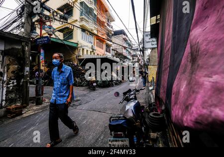 Un homme âgé, portant un masque, marche le long de la route à Talat Noi, Bangkok, Thaïlande Banque D'Images