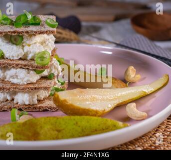 Sandwich au pain croustillant avec fromage cottage et ciboulette servi en tranches poires sur une assiette pour le petit déjeuner Banque D'Images