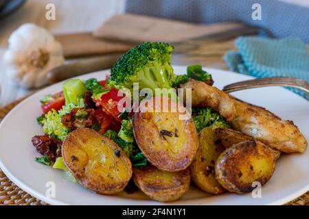 salade de brocoli méditerranéenne et pommes de terre au romarin rôties servies en tant que accompagnement sur une assiette avec poisson frit Banque D'Images