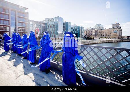 Berlin, Allemagne. 22 mars 2021. Des personnes vêtues de « rebelles bleus » se tiennent sur le pont Marschall lors d'une représentation du mouvement de protection de l'environnement « rébellion d'extinction » à l'occasion de la Journée mondiale de l'eau sous la devise « protéger l'eau - arrêter la fracturation dans le monde entier » ; le bâtiment Reichstag peut être vu en arrière-plan. Credit: Christoph Soeder/dpa/Alay Live News Banque D'Images