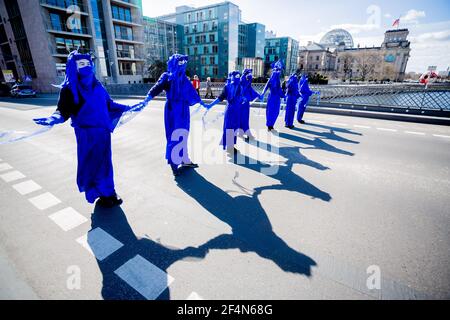 Berlin, Allemagne. 22 mars 2021. Des personnes vêtues de « rebelles bleus » se tiennent sur le pont Marschall lors d'une représentation du mouvement de protection de l'environnement « rébellion d'extinction » à l'occasion de la Journée mondiale de l'eau sous la devise « protéger l'eau - arrêter la fracturation dans le monde entier » ; le bâtiment Reichstag peut être vu en arrière-plan. Credit: Christoph Soeder/dpa/Alay Live News Banque D'Images