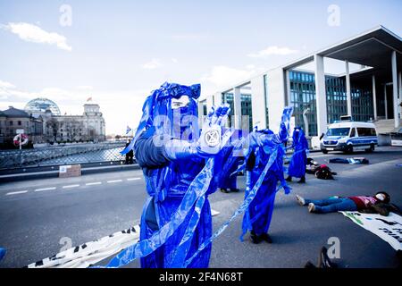 Berlin, Allemagne. 22 mars 2021. Des personnes vêtues de « rebelles bleus » se tiennent sur le pont Marschall lors d'une représentation du mouvement de protection de l'environnement « rébellion d'extinction » à l'occasion de la Journée mondiale de l'eau sous la devise « protéger l'eau - arrêter la fracturation dans le monde entier » ; le bâtiment Reichstag peut être vu en arrière-plan. Credit: Christoph Soeder/dpa/Alay Live News Banque D'Images