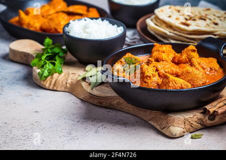 Curry de poulet dans une sauce épicée avec du riz et du pain de chapati, fond sombre. Concept de cuisine indienne. Banque D'Images