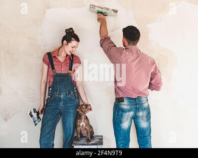 Charmant, adorable chiot de couleur marron et un couple marié qui fait des réparations. Gros plan, intérieur. Lumière du jour. Concept de soins, éducation, dressage d'obéissance Banque D'Images
