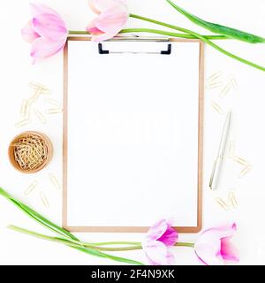 Concept d'espace de travail avec presse-papiers, stylo, fleurs de tulipe rose et accessoires sur fond blanc. Flat lay, vue de dessus Banque D'Images