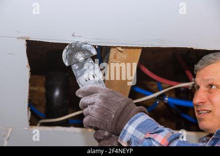 Entretien réparation travaux de remplacement cloison sèche endommagée sur la découpe des ouvriers plaques de plâtre avec outils électriques de construction Banque D'Images