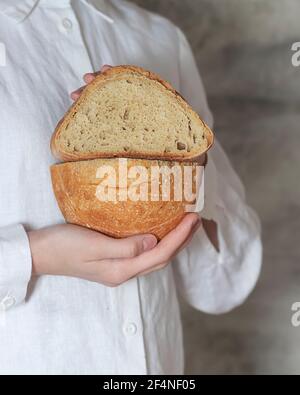 La boulangère femelle tient du pain bio artisanal fait maison, frais du four. Pain au levain maison. Plats faits maison. Préparation des aliments. Banque D'Images