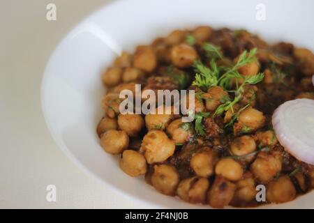 Sauce épicée aux pois chiches blancs faite en trempant les pois chiches pendant la nuit et cuits dans une sauce d'oignons, de tomates, de gingembre, d'ail et d'épices. Prise de vue sur fond blanc Banque D'Images