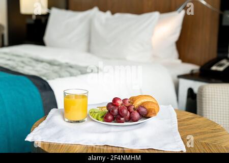 Plateau avec petit déjeuner sur une petite table en bois devant de caméra contre lit dans une des chambres de contemporain hôtel de luxe Banque D'Images