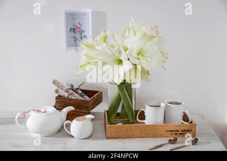 Moscou, Russie - 25 décembre 2020, UN bouquet de lys blancs dans un vase en verre sur une table avec deux grandes tasses de café, une théière, des cuillères et un pot à lait. Banque D'Images