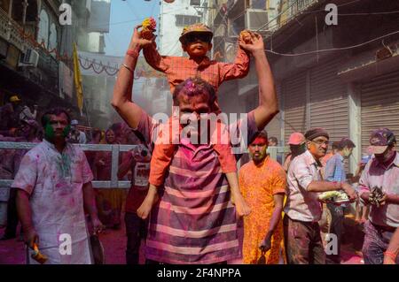 Un père danse avec son fils au-dessus de ses épaules lors d'un festival Holi à Kolkata, en Inde. Banque D'Images