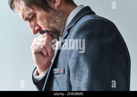 Homme d'affaires pensif fatigué surchargé de pensées contemplant la main sur le menton, portrait sélectif de mise au point Banque D'Images