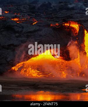 Lave en fusion s'écoulant d'une petite éruption volcanique au Mont Fagradalsfjall, près de la capitale de Reykjavik, dans le sud-ouest de l'Islande, en mars 2021. Banque D'Images