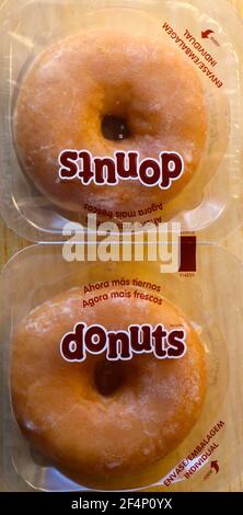 Photo de deux beignets espagnols ronds et sucrées, non sains, emballés individuellement dans un emballage plastique à ouverture facile vu d'en haut Banque D'Images