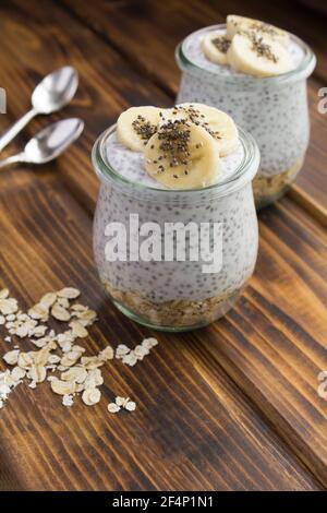 Pudding au chia, flocons d'avoine et banane dans les pots de verre le fond en bois Banque D'Images