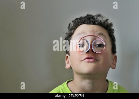 garçon regardant à travers des jumelles rouleau de papier sur fond blanc photo Banque D'Images