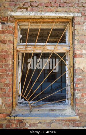Grille de sécurité en fer rouillé sur une fenêtre cassée dans les ruines abandonnées bâtiment vertical Banque D'Images