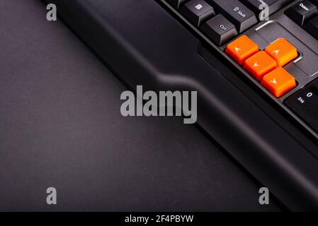 Touches fléchées orange sur un clavier noir, touches haut, bas, gauche, droite sur un clavier d'ordinateur de jeu. Banque D'Images