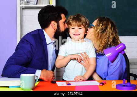 Heureux parents embrassant petit fils. La scolarité familiale ensemble. Éducation des enfants. Rôle parental. Banque D'Images