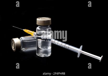 Vaccins, toxine botulinique et ampoules d'insuline concept thème avec des flacons en verre avec liquide clair à côté d'une seringue et une aiguille hypodermique isolée sur b Banque D'Images