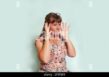 Une femme de race blanche d'âge moyen à l'aspect naturel avec des cheveux blonds foncés et un regard de pleurs bouleversés sur son visage. Banque D'Images