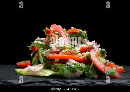 Salade d'endives fraîches avec tomates cerises et sur la plaque noire coin, verser de l'huile d'olive Banque D'Images