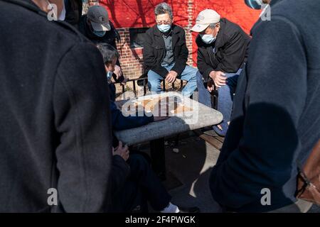 Les New-Yorkais d'origine asiatique et américaine passent une journée de printemps chaude et paisible à Columbus Park en jouant aux cartes, en jouant aux échecs chinois ou tout simplement en appréciant la journée. Park a l'air complètement paisible et différent le lendemain après un grand rassemblement contre les crimes de haine entre les Américains et les Asiatiques. Le seul rappel concerne les fleurs et une affiche à la sculpture du Dr. Sun Yat-sen. Il y a des femmes et des hommes qui jouent aux cartes sur des tables séparées, tous portent des masques, mais la majorité des femmes portent aussi des gants de protection. (Photo de Lev Radin/Pacific Press) Banque D'Images