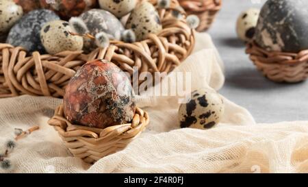 Composition de Pâques - plusieurs oeufs en marbre peints avec des teintures naturelles dans un nid en osier et des paniers. Banque D'Images