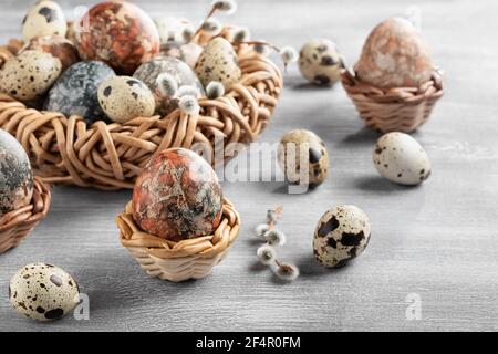 Composition de Pâques - plusieurs oeufs en marbre peints avec des teintures naturelles dans un nid en osier et des paniers. Banque D'Images