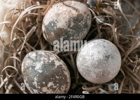 Composition Pâques - plusieurs œufs en marbre peints avec des teintures naturelles dans un nid en papier sur la table, vue du dessus Banque D'Images