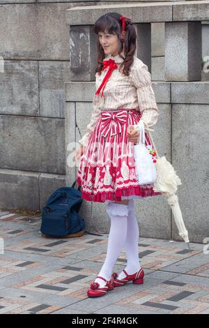 Photo pleine longueur de japonais lolita portant une jupe rouge et blanche, de longues chaussettes blanches à volants et de chaussures rouges posant pour la photographie, Harajuku, Tokyo, Japon Banque D'Images