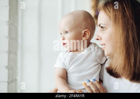 Joli bébé et sa mère près de la fenêtre. Banque D'Images