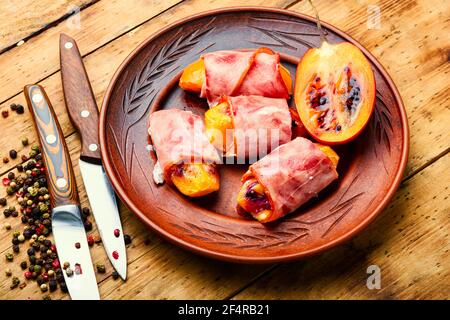 Morceaux de Tamarillo emballés et cuits avec du jambon et du bacon Banque D'Images