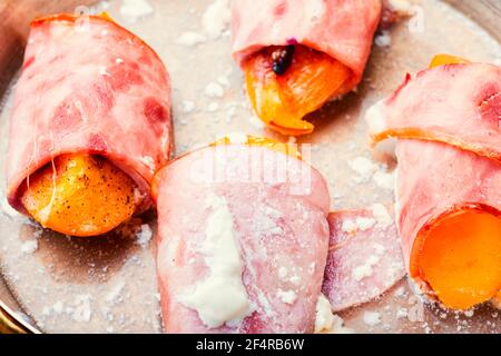 Morceaux de Tamarillo emballés et cuits avec du jambon et du bacon Banque D'Images