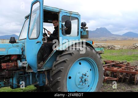 Un grand vieux tracteur bleu avec des charrues de champ à l'automne. Banque D'Images