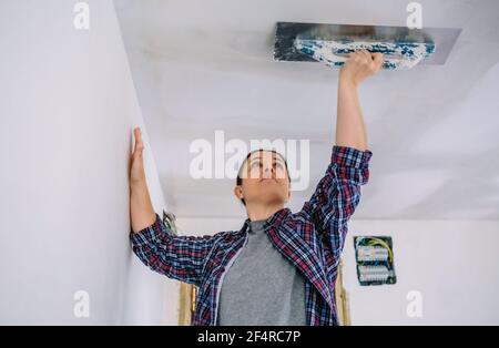 Bricklayer lissage du plafond de plâtre avec la truelle Banque D'Images