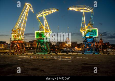 Vieilles grues portuaires illuminées sur un boulevard de la ville de Szczecin la nuit Banque D'Images