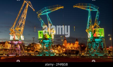 Vieilles grues portuaires illuminées sur un boulevard de la ville de Szczecin la nuit Banque D'Images