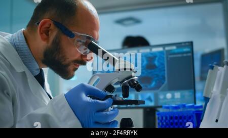 Technicien de laboratoire examinant les échantillons et les liquides à l'aide d'un microscope dans un laboratoire équipé. Scientifique travaillant avec divers échantillons de bactéries, de tissus et de sang, recherche pharmaceutique pour les antibiotiques Banque D'Images