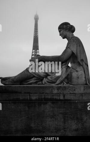 Statue près de la tour Eiffel en noir et blanc sur un ciel nuageux Banque D'Images