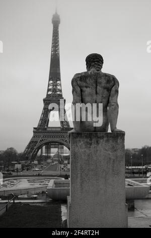 Statue près de la tour Eiffel en noir et blanc sur un ciel nuageux Banque D'Images