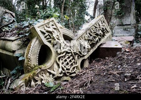 Une tombe brute celte déchue se trouve parmi les tombes surcultivées et délabrées, cimetière victorien Nunhead, Londres, Royaume-Uni. Banque D'Images