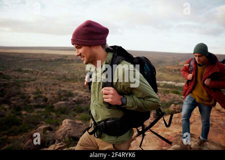 Deux amis mâles avec sac à dos et montagne d'escalade de casquette d'hiver Banque D'Images