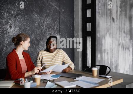 Portrait de deux femmes d'affaires réussies discutant du projet à table dans le bureau gris, espace de copie Banque D'Images