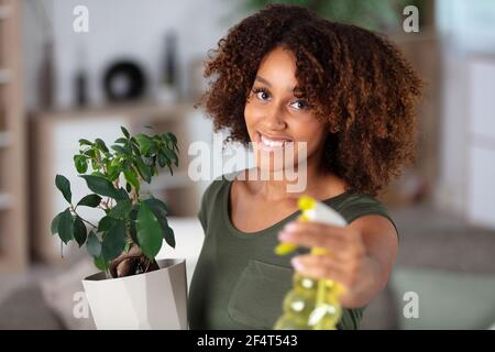 une jeune femme pulvérise des plantes dans des pots de fleurs Banque D'Images