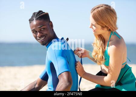 couple portant des combinaisons sur la marche du surf Banque D'Images