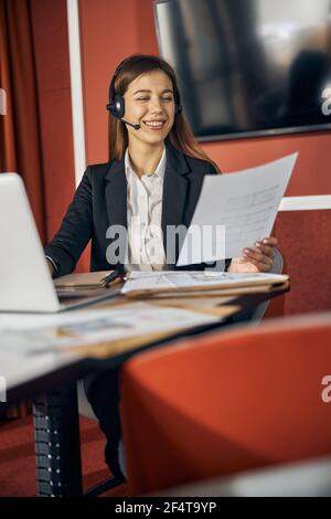 Femme très animée avec un dessin technique assis à la réception Banque D'Images