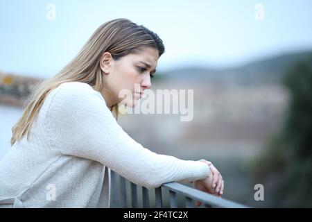 Triste femme regardant dans un balcon de la maison se plaignant seule dans une ville Banque D'Images