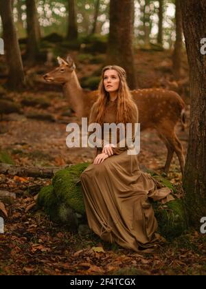 Fille REDHEAD avec cerf dans une longue robe Banque D'Images